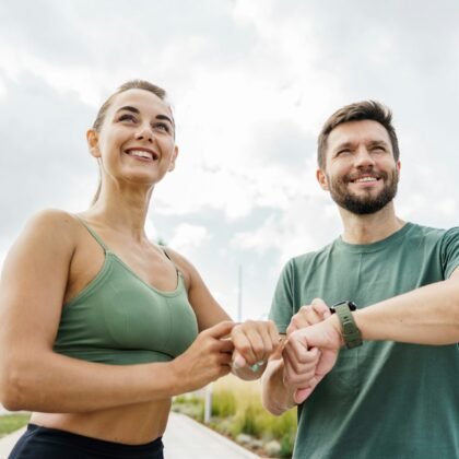 Smiling couple checking fitness progress on smartwatch after workout, urban park.